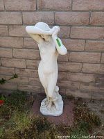 Front view of the female concrete statue planter, showing the figure with arms raised across face.