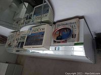 Boxes and stacks of newspapers from the 1984 Olympics shown with various headlines and images.