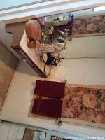 Vanity counter with decorative items including wooden and ceramic decor, costume jewelry clutches, floral tapestry wall hanging and red towels under a wall mirror.