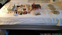 Full spread of assorted antique Christmas ornaments and decorations arranged on a bed, showing variety of items including boxes, figurines, and baubles