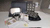 Overview of bakeware items including pans, hand mixer, sifter, and towels arranged on countertop.