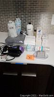 Full overview of all bath items on a white countertop with tiled backsplash for scale and detail