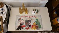 Photo showing the welcome friends Christmas door mat with festive animals and camper design, placed on a table.