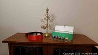 Wide view showing all items: a red round box with 5 large egg ornaments inside, a green box with 12 smaller eggs, and a gold metal ornament holder with a star on top.