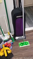 Oreck Classic Pro vacuum with green mop and other cleaning tools