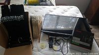 Box and collection of black pant hangers and flocked hangers on bed