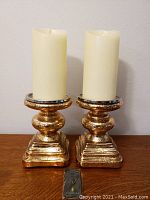 Front view of two mercury glass lighted candle holders with ivory LED candles and remote control.