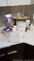 Therabath paraffin wax bath with cover and various accessories including hand mitts, foot boots, plastic bags, and Aveda hand relief creams displayed on counter