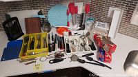 Overview of kitchen utensils including cutlery organizer, kitchen knives, spatulas, cutting boards, serving spoons, and other small kitchen tools.