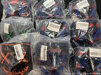 13 black plastic glow masks with red paint and blue LED light wiring in sealed plastic bags showing quantity and storage condition