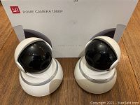 Two YI Dome Cameras 1080P next to their original packaging box showing family pack labeling.