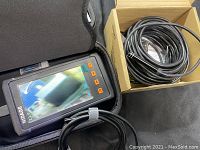 First image showing one Nidage endoscope unit powered on, screen displaying external view, and coiled black inspection cable in cardboard box.