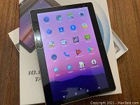 Tablet powered on showing Android home screen with app icons including Calculator, Calendar, Camera, Downloads, Email, Browser, Clock, Contacts, FM Radio, and Play Store