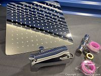 Large square chrome shower head alongside chrome faucet body and rolled pink plumber's tape.