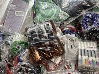 Mixed lot of various packaged craft supplies and objects wrapped in plastic showing diverse colors and materials.