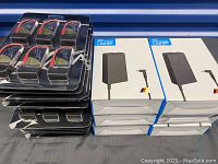Photo showing multiple blister packs of six Tattu batteries stacked beside boxed AC chargers.