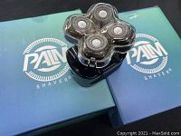 Two Palm shaver units shown sitting on their branded boxes displaying the shaver heads and overall condition.