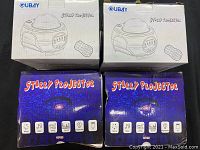 Two retail boxes with printed star projector graphics and remote control illustration, one with blue starry night design and another white with product line drawing, showing the brand GUBAY and product name Starry Projector.