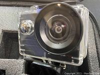 Close-up of the action camera showing large fisheye lens and clear waterproof housing.