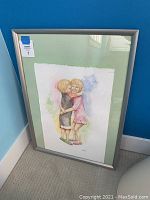 Full view of the framed artwork depicting two children hugging, showing the frame style and artwork placement.