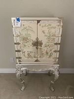 Front view of closed jewelry cabinet on silver-tone carved stand