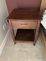 Front view of one wooden nightstand showing drawer and open shelf underneath