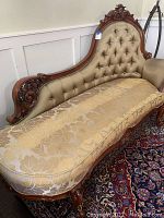 Full view of chaise lounge showing overall design, upholstery, and carved wooden frame