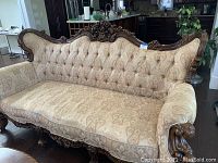 Front view of three-person sofa with carved wood frame and beige paisley upholstery