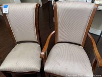 Pair of dining chairs, one with armrests and one without, showing fabric upholstery and wooden frames in used condition