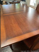 Extended wooden dining table with smooth reddish-brown finish surface showing wood grain.