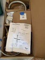 View of the faucet spout, installation instructions and hardware inside the original box.