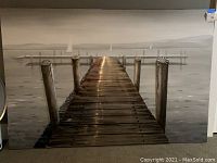 Full view of the canvas wall artwork depicting a wooden pier extending into calm water with boats in the background.
