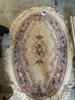 Full view of oval area rug showing floral design and fringes at the edges.
