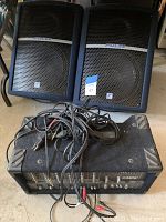 Two angled black Pulse speakers with metal grilles and a synthesizer/amplifier unit with control knobs and cables in front