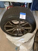 Full view of the tire mounted on alloy rim standing upright indoors on a concrete floor.