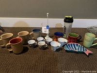 Photo showing all items in the lot including assorted mugs, espresso set, fish serving dish, and water bottle.