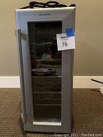 Front view of silver and black Magnasonic mini wine fridge with glass door and metal handle
