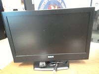 Front view of the RCA 24-inch LCD TV/DVD combo showing the screen and attached stand with remote placed in front.