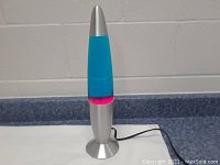 Front view of the retro lava lamp showing its silver base, blue liquid, pink lava, and tapered shape.