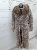 Full view of the full length fox fur coat displayed on a mannequin, showing the shape, length, and collar detail.