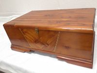 Front angled view of the vintage wooden chest showing top, sides, and latch closure
