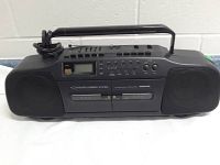 Full view of the black portable boombox stereo with speakers, handle, and control panel on top.