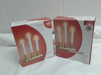 Two boxed 3 Lite Candeliers by Avenue Noël with retail packaging showing candle lights.