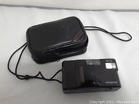 Olympus AF-10 camera with black carrying case laid flat on white surface.