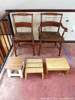 Two wooden chairs and three small wooden stools arranged on carpeted floor, showing overall lot contents.