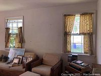 View of two windows in a room with curtains; left window has short curtain panels and right window has longer floral patterned curtains.