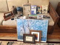 Overview of all items showing framed prints, pottery, model ships in bottles, books, and glass art on a couch and floor