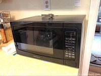 Front view of black Insignia microwave on countertop.