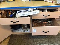 Three pint glass mason jars and six half-pint glass storage jars inside beige drawers; top drawer contains boxed knives.
