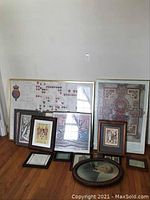 Full view of 15 pieces of framed artwork arranged on the floor showing variety in size and style.
